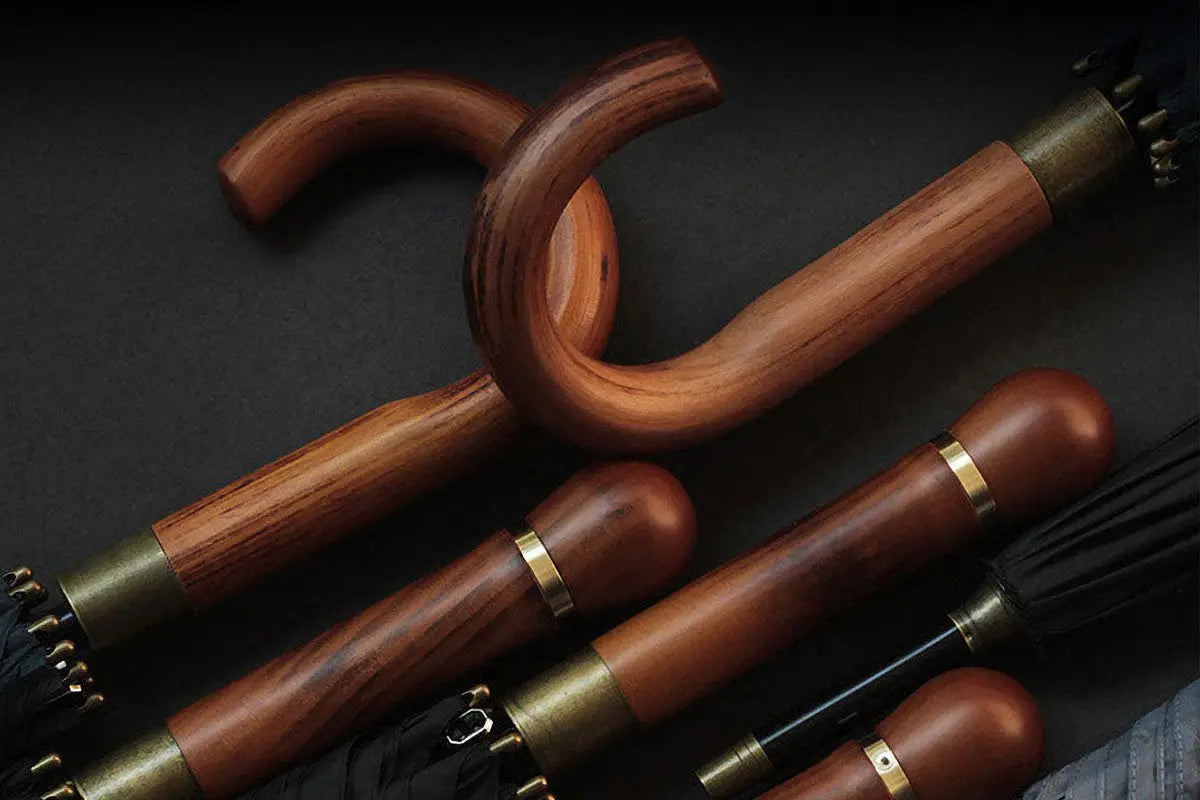 Plusieurs poignées de parapluie en bois massif avec des colliers en laiton montrant le grain naturel et les formes de crosse et de Derby